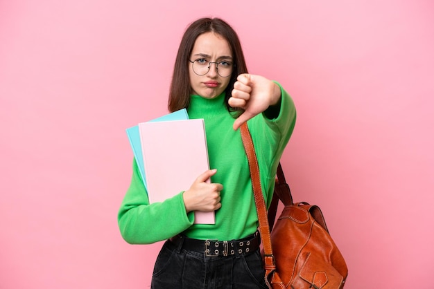 Jonge student Oekraïense vrouw geïsoleerd op roze achtergrond duim omlaag met negatieve expression