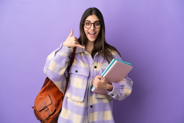 Jonge student vrouw geïsoleerd op paarse achtergrond telefoon gebaar maken. Bel me terug teken