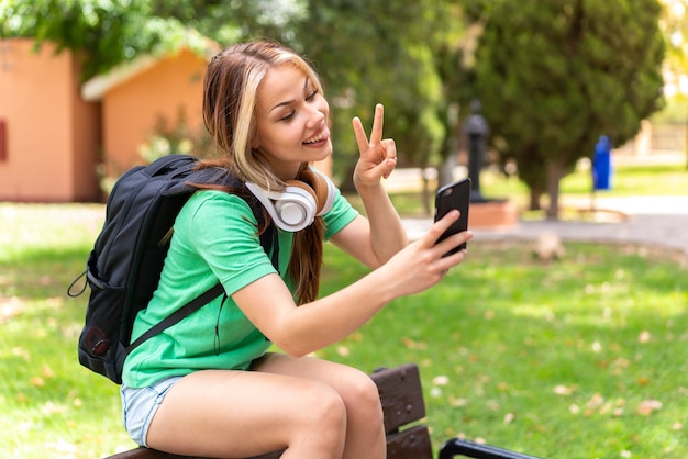 Jonge student vrouw in de buitenlucht met behulp van mobiele telefoon