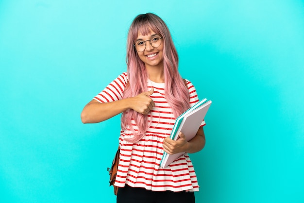 Jonge student vrouw met roze haren geïsoleerd op blauwe achtergrond geven een duim omhoog gebaar
