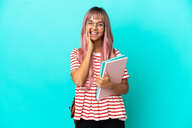 Jonge student vrouw met roze haren geïsoleerd op blauwe achtergrond schreeuwen met wijd open mond