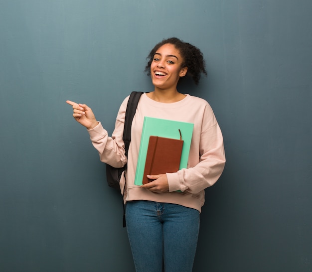 Jonge student zwarte vrouw wijst naar de kant met vinger Ze houdt boeken