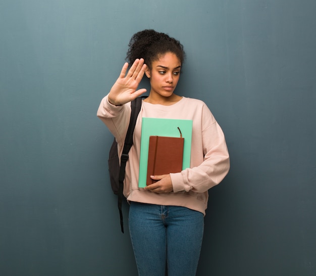 Jonge student zwarte zetten hand in de voorkant. Ze houdt boeken.