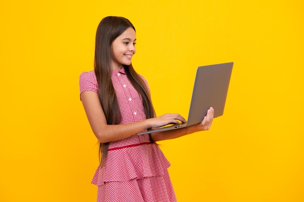 Jonge studente houdt computer Grappige leerling met laptop geïsoleerd op gele achtergrond Terug naar school