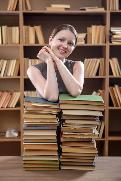 Jonge studente leunde op een stapel boeken in de bibliotheek