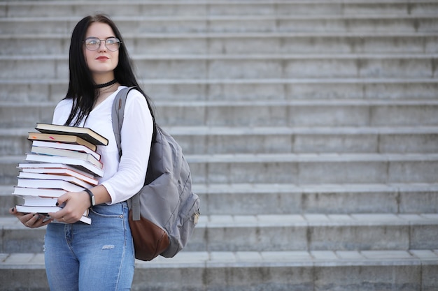 Jonge studente op straat met een rugzak en boeken