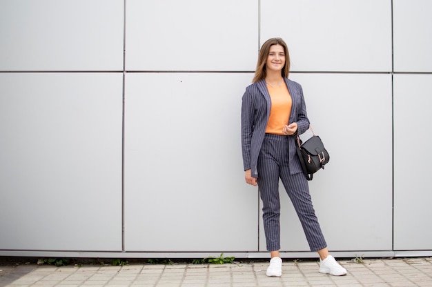 Jonge studente staat tegen een grijze muur in de straat