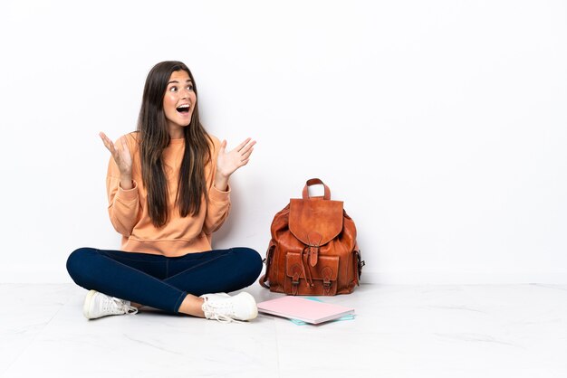 Jonge studenten Braziliaanse vrouw, zittend op de vloer met verrassingsgelaatsuitdrukking