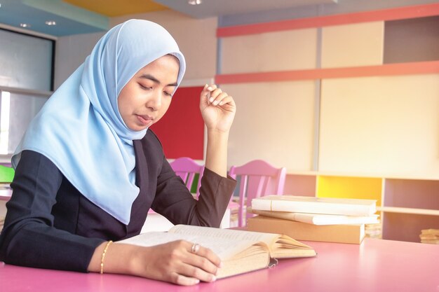 Jonge studenten Islamitische vrouw. Ze zit en leest een boek.