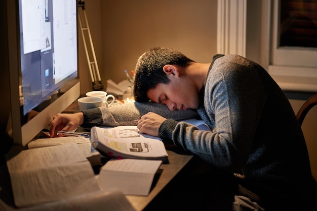 Jonge studentenboeken en slapen in de buurt van het scherm of tot diep in de nacht studeren of op tafel rusten en lezen voor onderzoek vermoeid onderzoek en hard werken voor testpapier of computer thuis