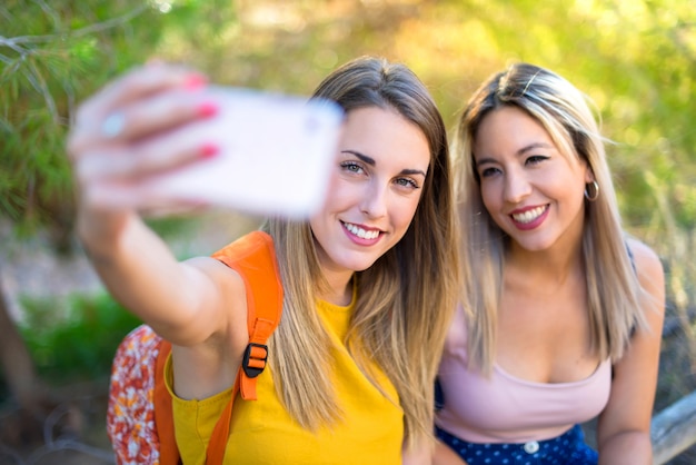 Jonge studentenmeisjes met rugzak in een park die een selfie maken