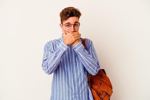 Jonge studentenmens die op witte muur wordt geïsoleerd die geschokt die mond behandelt met handen.