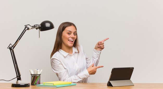 Jonge studentenvrouw die aan haar bureau werkt dat aan de kant met vinger richt