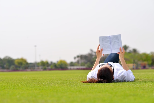 Jonge studentenvrouw die een boek leest en in het park studeert