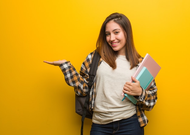 Jonge studentenvrouw die iets met hand houdt