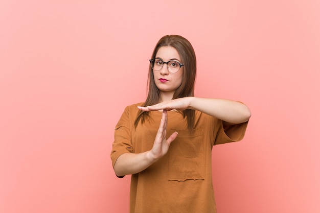 Jonge studentenvrouw die oogglazen draagt die een time-outgebaar tonen.