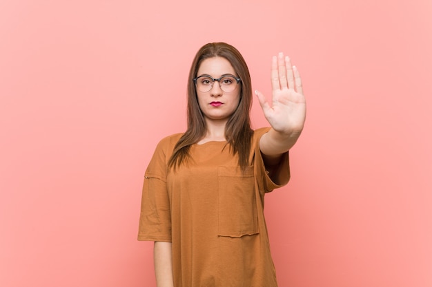 Jonge studentenvrouw die oogglazen dragen die zich met uitgestrekte hand bevinden die eindeteken tonen, die u verhinderen.