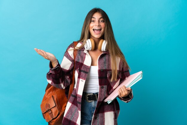 Jonge studentenvrouw die op blauw met geschokte gezichtsuitdrukking wordt geïsoleerd