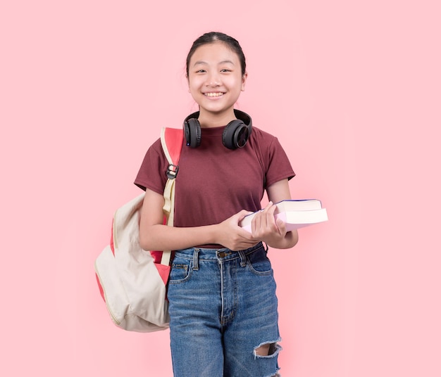 Jonge studentenvrouw die op de middelbare school bij de camera roze muur glimlachen