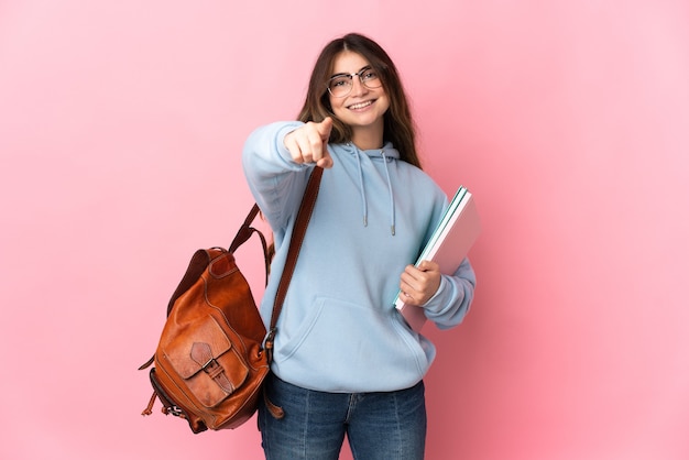 Jonge studentenvrouw die op roze wijzend front met gelukkige uitdrukking wordt geïsoleerd