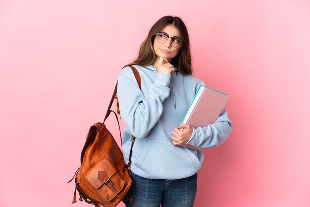 Jonge studentenvrouw die op roze wordt geïsoleerd die twijfels heeft en denkt