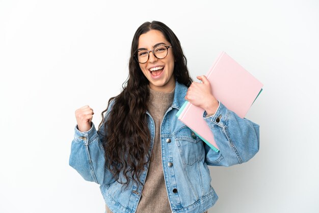 Jonge studentenvrouw die op witte achtergrond wordt geïsoleerd die een overwinning viert