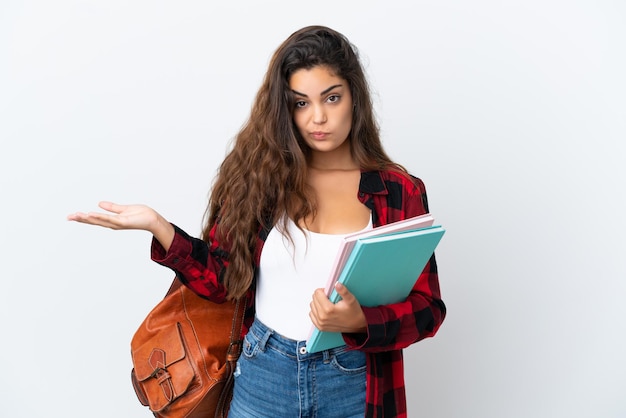 Jonge studentenvrouw die op witte achtergrond wordt geïsoleerd die twijfels heeft terwijl het opsteken van handen