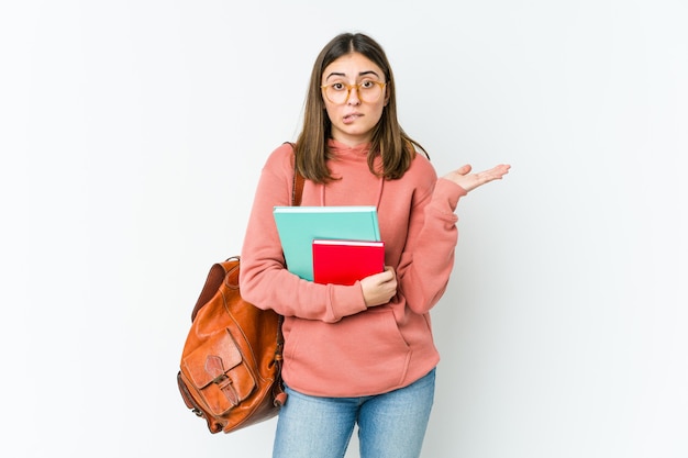 Jonge studentenvrouw die verward en twijfelachtig schouders ophaalt