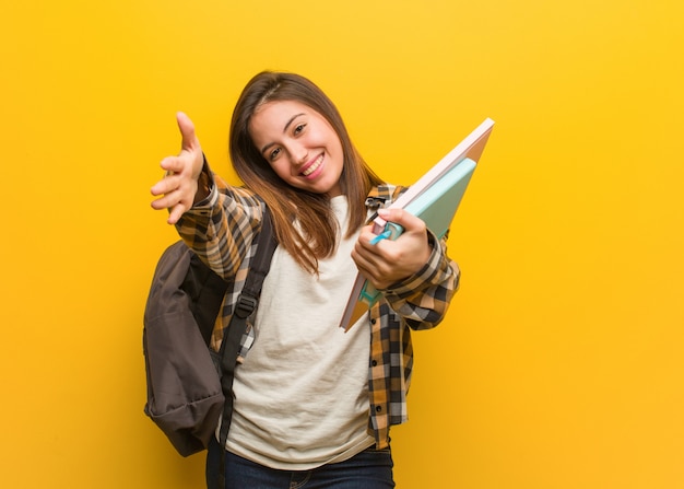 Jonge studentenvrouw die zeer gelukkig een omhelzingsvoorzijde geeft