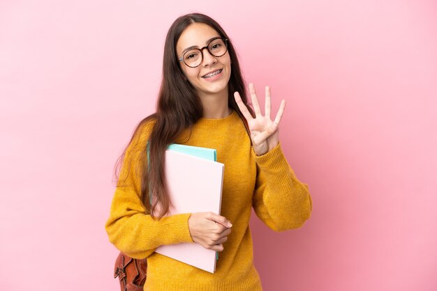 Jonge studentenvrouw over geïsoleerde achtergrond gelukkig en telt vier met vingers