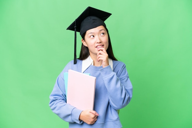 Jonge studentenvrouw over geïsoleerde chroma key achtergrond en omhoog kijkend