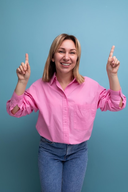 Jonge succesvolle blonde carrièreleidersvrouw in een roze blouse toont haar handen naar het lege