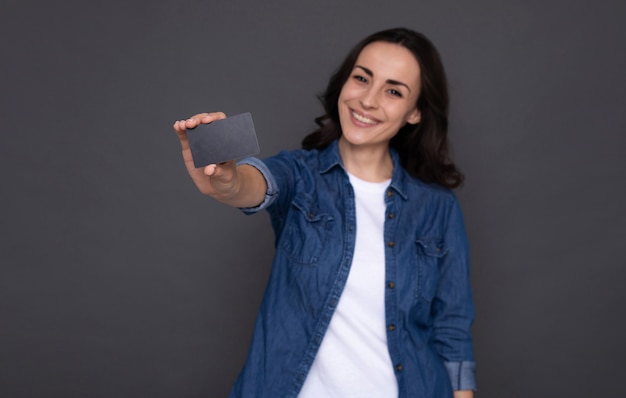 Jonge succesvolle gelukkige vrouw met een creditcard in de hand tijdens online winkelen