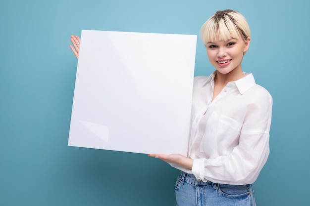 Jonge succesvolle mooie blonde kantoormedewerker vrouw in een wit overhemd en spijkerbroek houdt een stuk papier