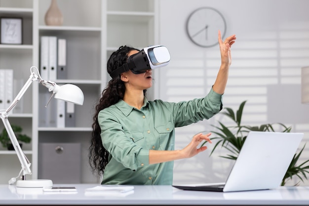 Jonge succesvolle vrouw op kantoor met behulp van vr-bril, virtual reality-simulator, dwarsgrafieken en
