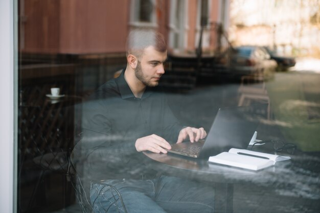 Jonge succesvolle zakenman die aan laptop werkt terwijl u in koffie zit