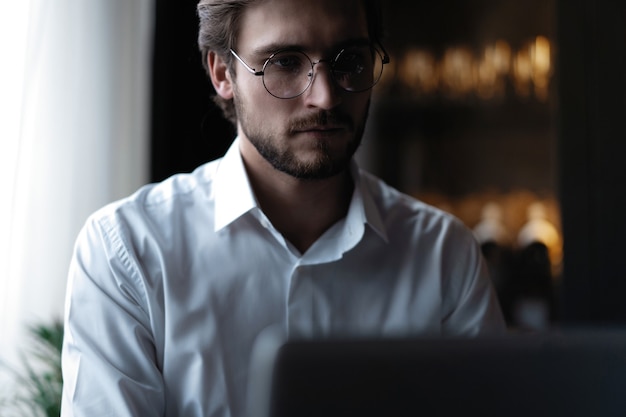 Jonge succesvolle zakenman die op een laptop werkt terwijl hij in een café zit.