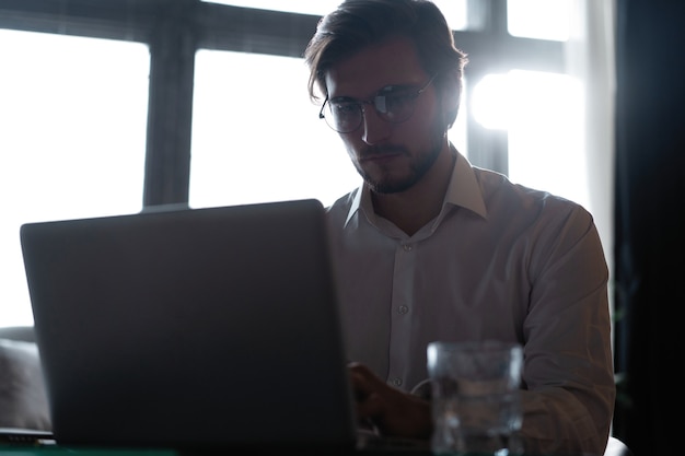 Jonge succesvolle zakenman die op een laptop werkt terwijl hij in een café zit.