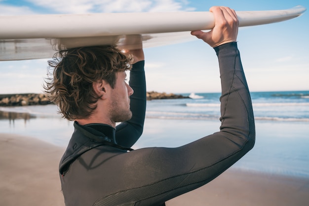 Jonge surfer die zijn surfplank steunt.