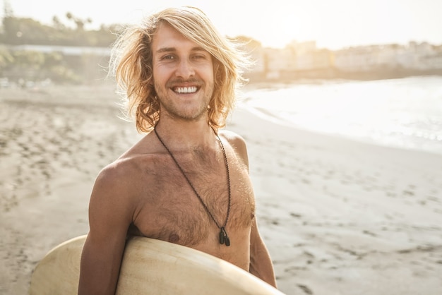 Jonge surfer man met surfplank op het strand bij zonsondergang - Focus op gezicht