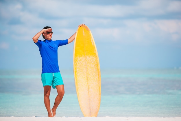 Jonge surfman op wit strand met gele surfplank