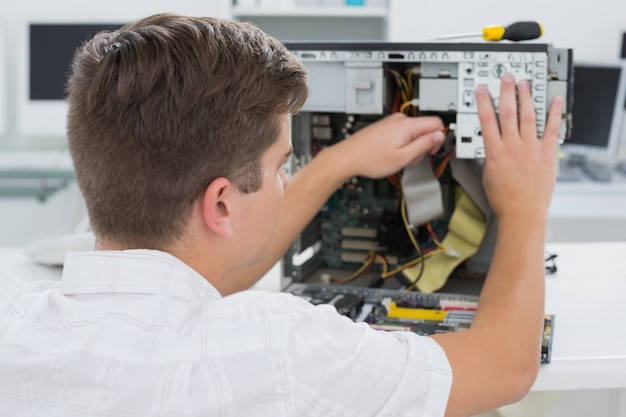 Foto jonge technicus die aan gebroken computer werkt