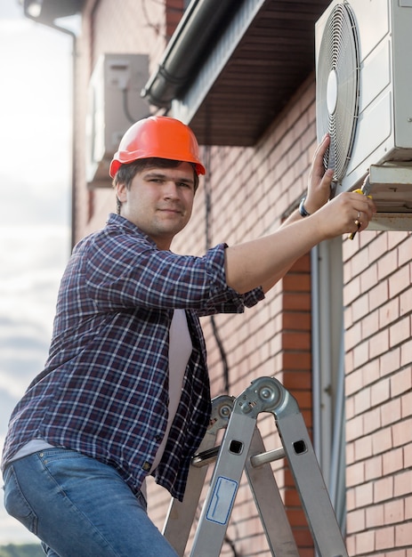 Jonge technicus die buiten airconditioning repareert