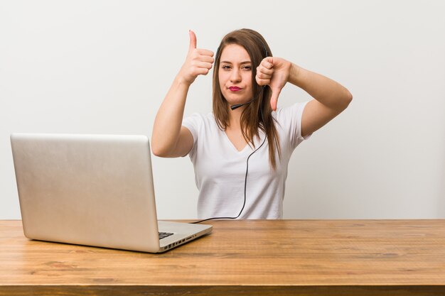 Jonge telemarketeer vrouw duimen opdagen en duimen naar beneden, moeilijk kiezen