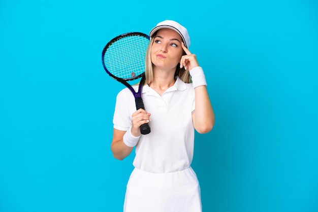 Jonge tennisser Roemeense vrouw geïsoleerd op blauwe achtergrond met twijfels en denken