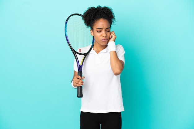 Jonge tennisser vrouw geïsoleerd op blauwe achtergrond gefrustreerd en die oren bedekt