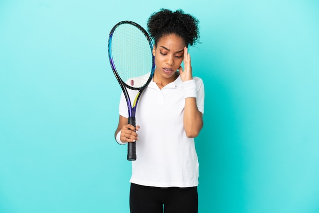 Jonge tennisser vrouw geïsoleerd op blauwe achtergrond met hoofdpijn