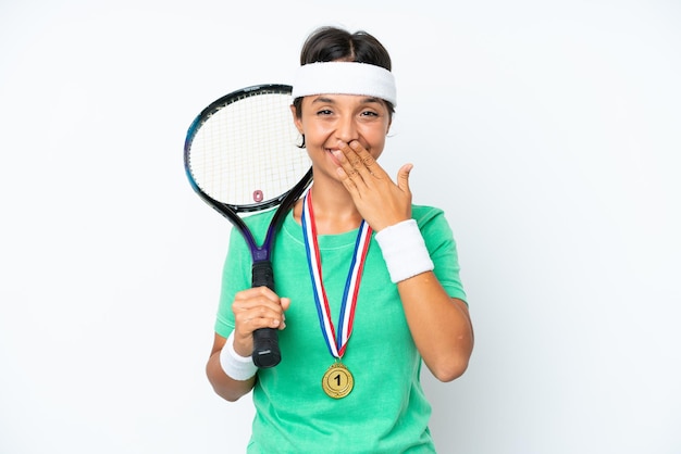 Jonge tennisser vrouw geïsoleerd op witte achtergrond blij en lachend voor mond met de hand