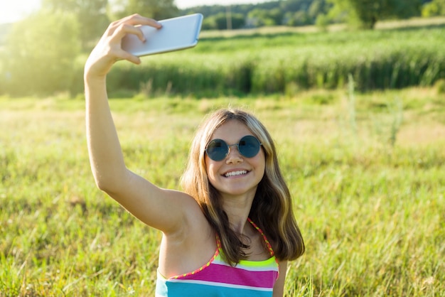 Jonge tiener die een smartphone gebruikt die selfie in het park doet.