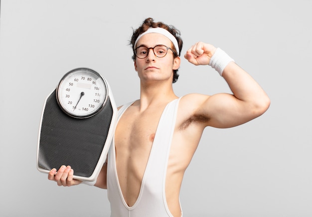 Jonge tiener man jonge gekke atleet die een succesvolle overwinning viert en een weegschaal vasthoudt